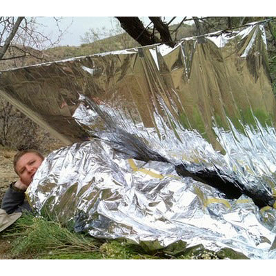 Silver emergency survival blanket sheet, reflective crinkled material over person