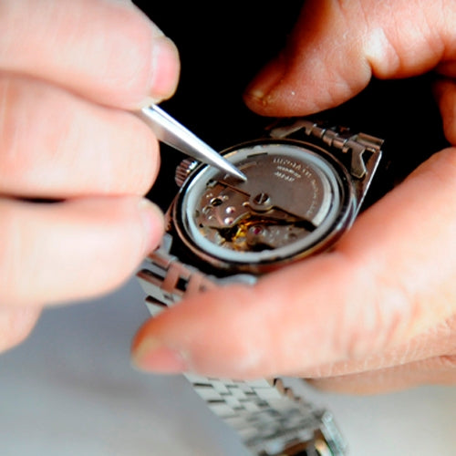 Hands using a precision screwdriver tip to adjust a watch component