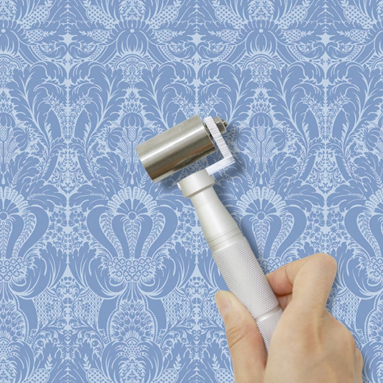 Hand using stainless steel wallpaper seam roller tool on patterned wall