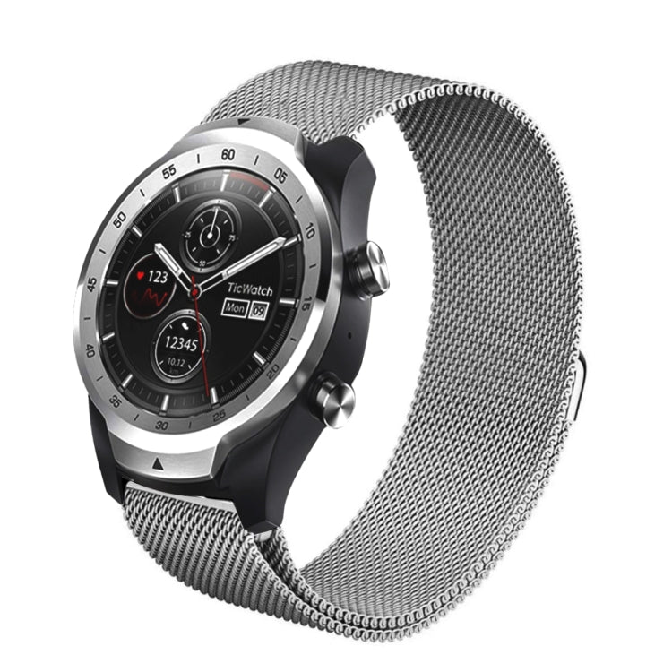 Silver milanese metal watch strap with mesh links and magnetic-style clasp, worn on watch.