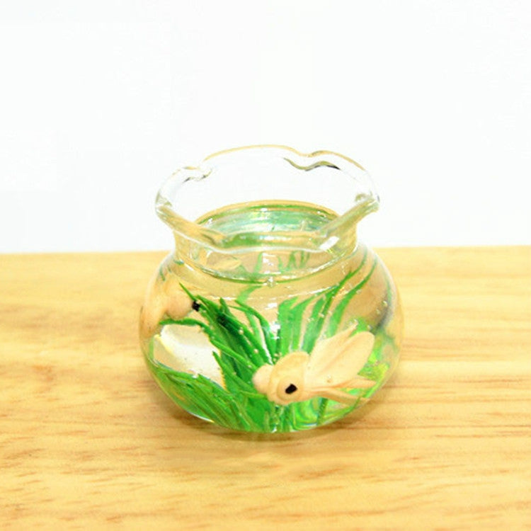 Miniature transparent glass fish tank with green plants and cream-colored fish