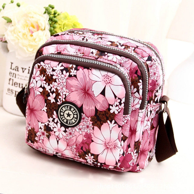 Women’s pink floral shoulder bag with multiple zip compartments, adjustable crossbody strap