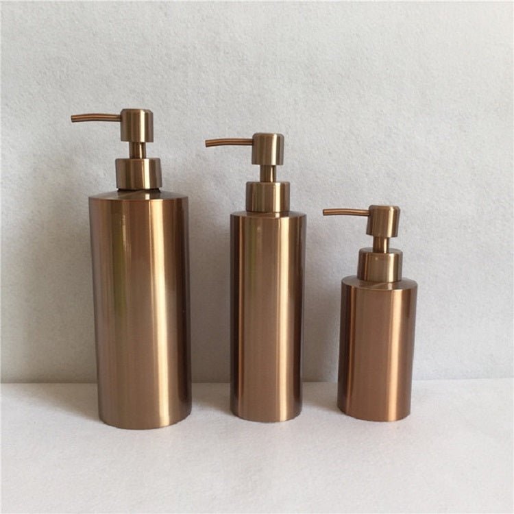 Three brushed bronze soap dispensers on counter, varying heights with pumps