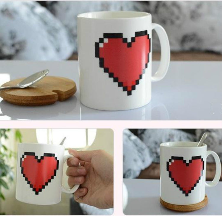 Temperature-changing heart mug with red pixel heart on white ceramic, held by hand