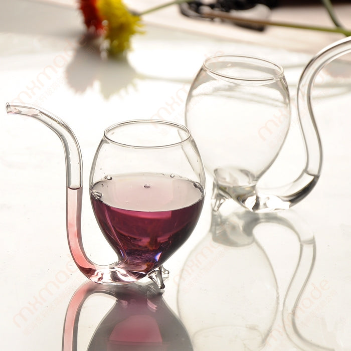 Set of clear glass juice mugs with straws, one with red drink, one empty