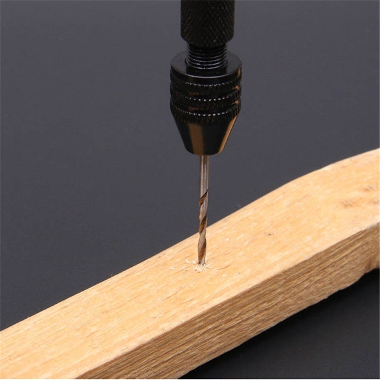 Manual drill bit drilling into light wood board from textured black chuck