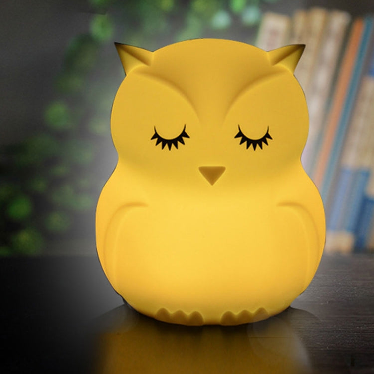 Golden yellow glowing silicone owl LED night light on tabletop