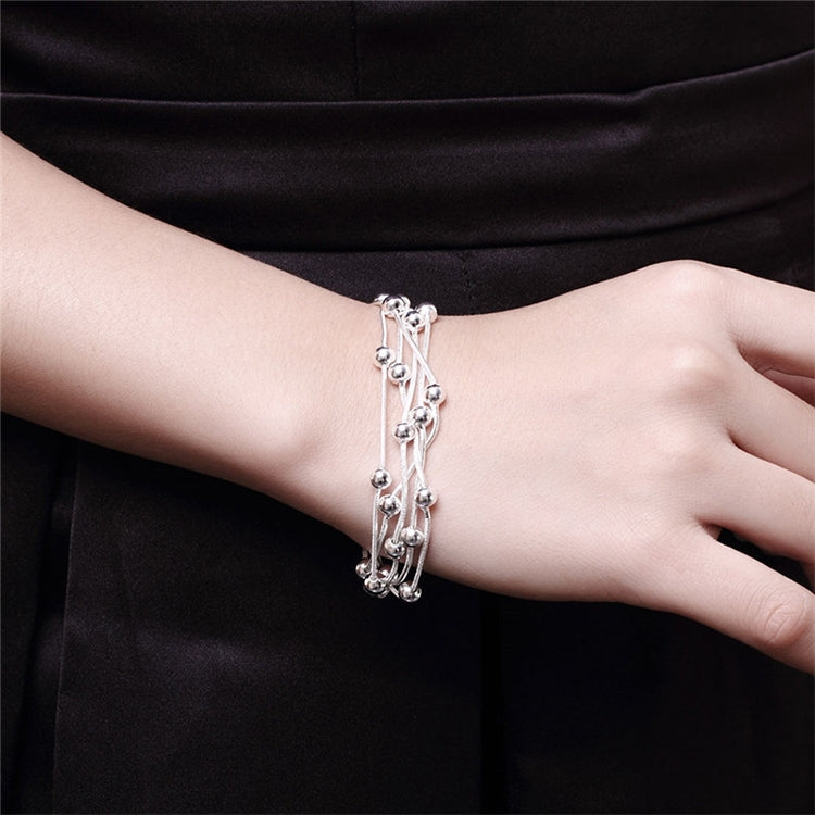 Silver plated bracelet worn on wrist with ball charms and layered chain cords