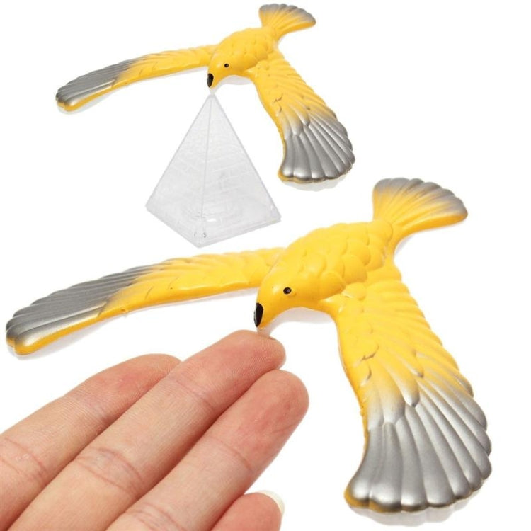 Yellow and gray eagle balance bird toy with clear triangular base, held in hand