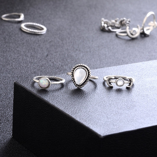 Silver-tone ring set on display with moon, opal-like teardrop, and starburst details