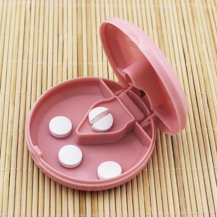 Round pink plastic medicine dispensing box with lid open and pill compartments visible