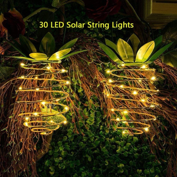 Solar pineapple lantern string lights in close-up, warm LED spiral coils and green leaf crown