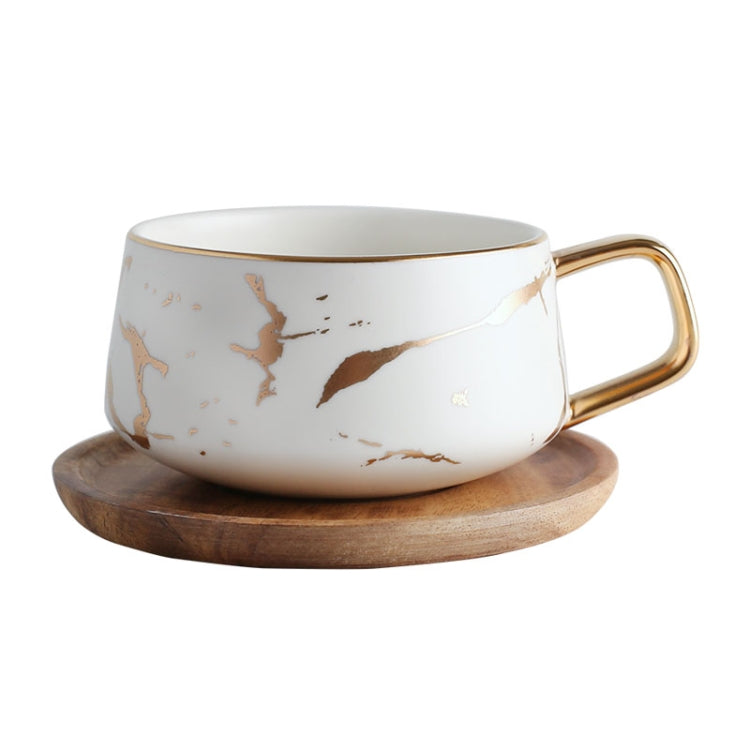 White ceramic tea cup mug with gold handle on a wooden tray, marble design