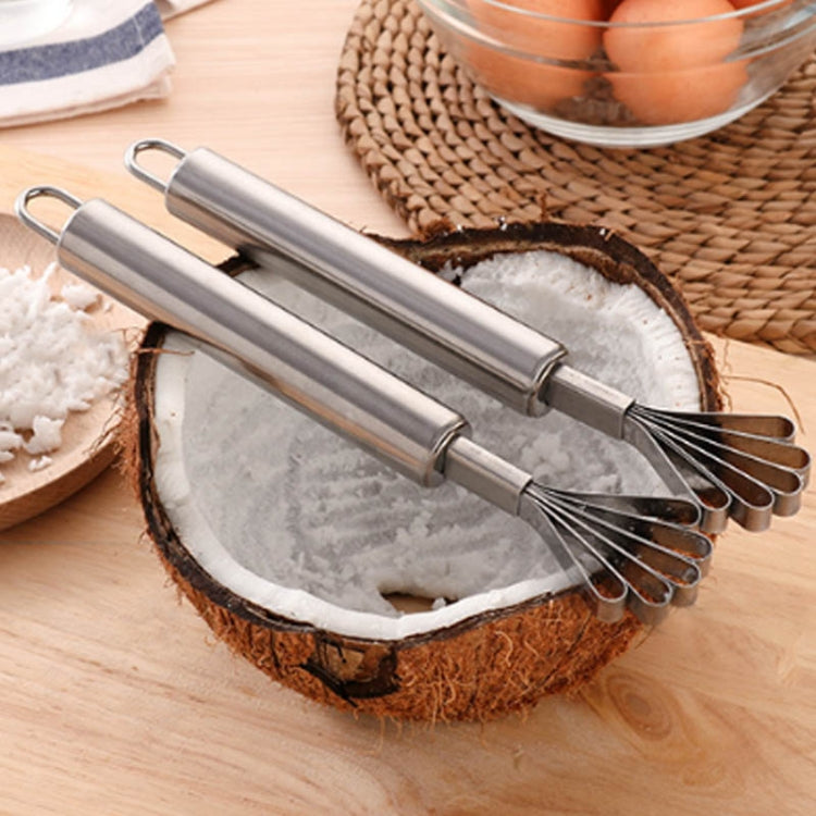 Two stainless steel coconut planers with whisk tines and loop handles over coconut half