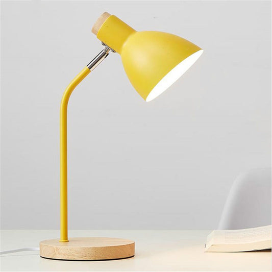 Yellow metal shade desk lamp on round wood base, angled spotlight.