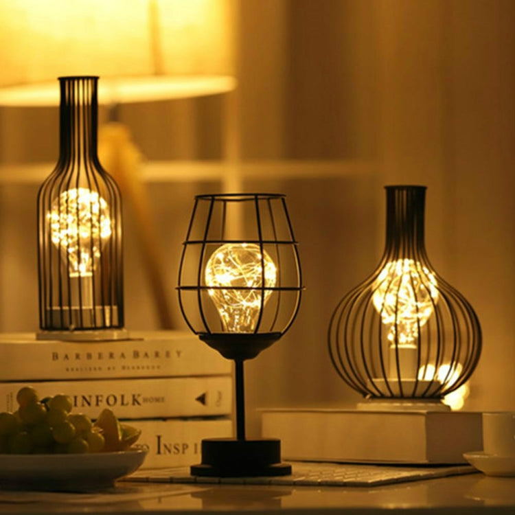 Three metal-caged LED table lamps with bottle silhouettes, warm ambient glow