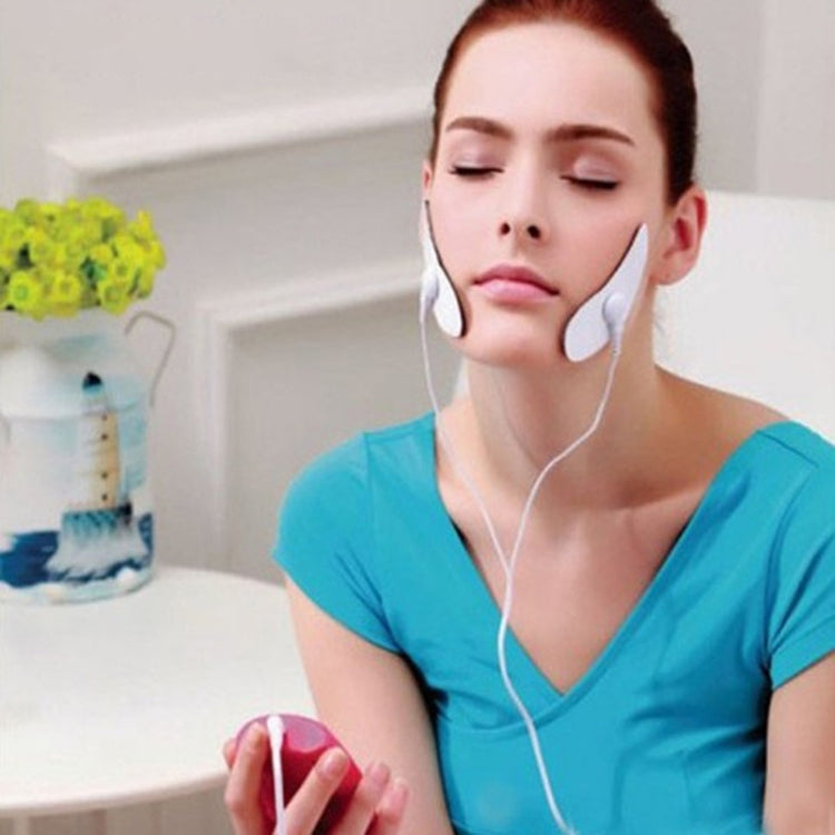 Woman wearing electrode pads on cheeks with pink EMS microcurrent face massager