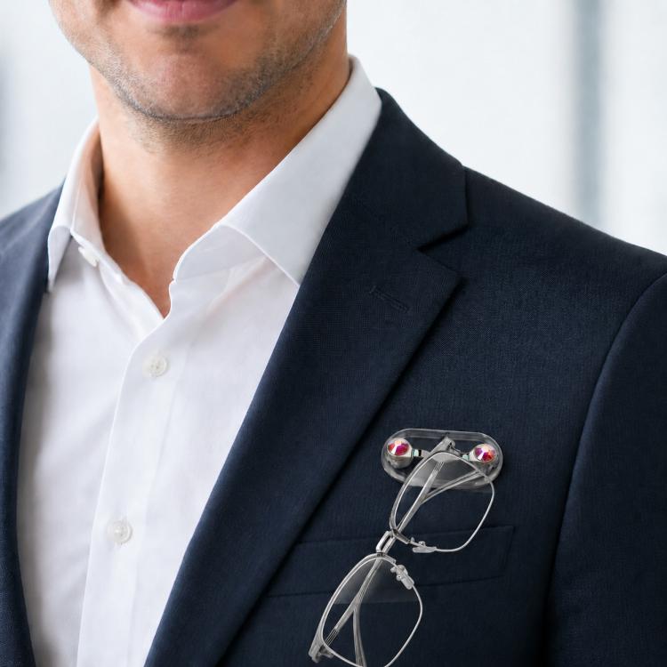 Magnetic glasses holder brooch clipped to a navy blazer lapel, holding eyeglasses