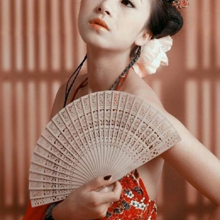 Beige folding hand fan held up, perforated lattice with ribbed edges