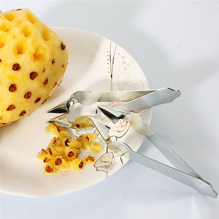 Stainless steel pineapple clip removing pineapple chunks from a plate