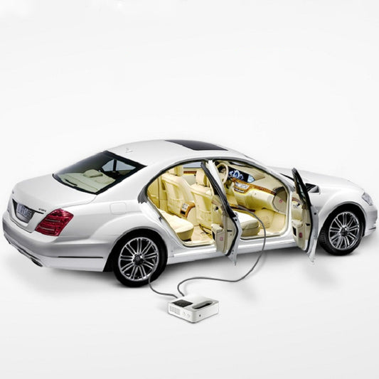White portable car tire air pump with power cable beside open-door sedan