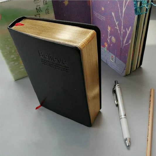 Ultra-thick faux leather notebook, black cover with gold-toned edges and corner tie.