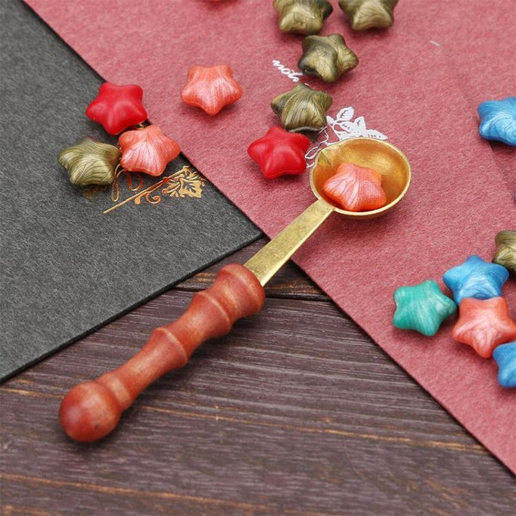 Wooden measuring spoon with red handle and gold scoop bowl