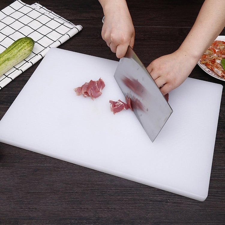 White square double-sided cutting board on counter, knife slicing meat