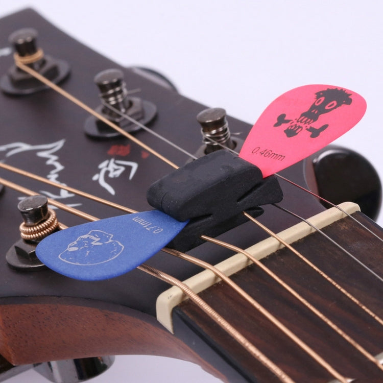 Black rubber guitar string head clip holding guitar strings and picks