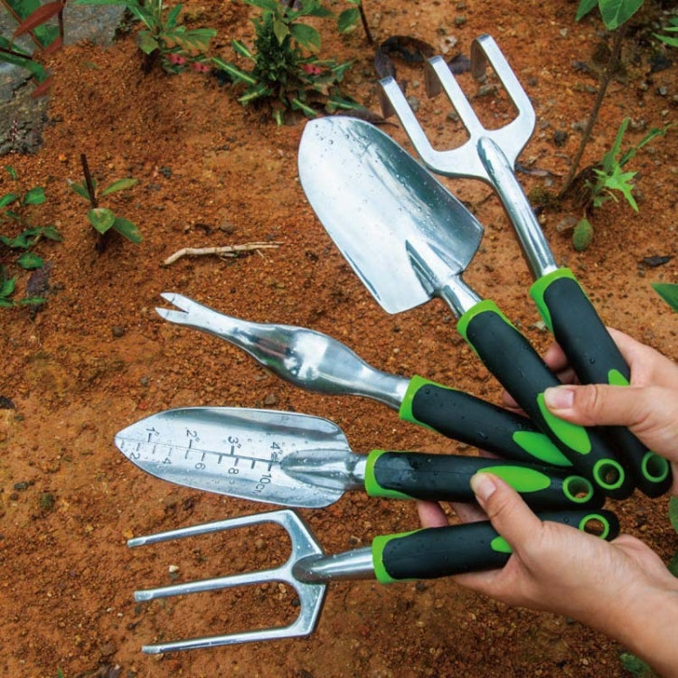 Aluminum garden tools set with shovels and weeder arranged on bare soil