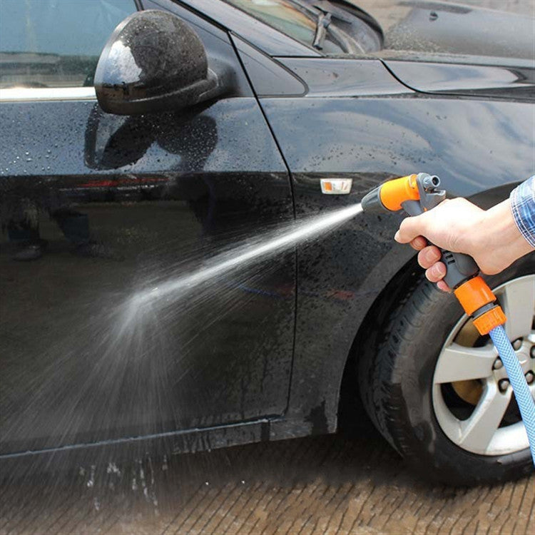 Garden hose nozzle sprinkler rinsing car surface with water jet from orange tip