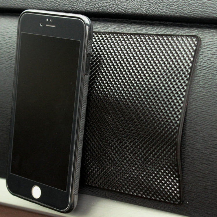 Black textured anti-slip mat holding a phone against a car surface