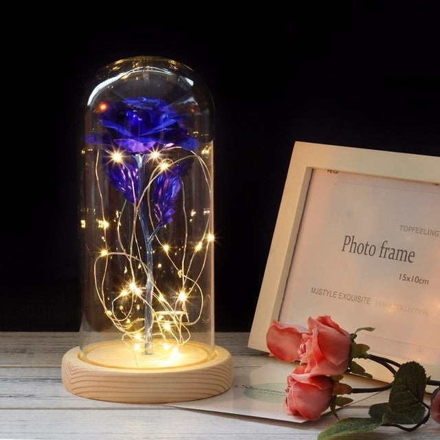 Blue rose LED in clear glass dome with warm string lights and round wooden base