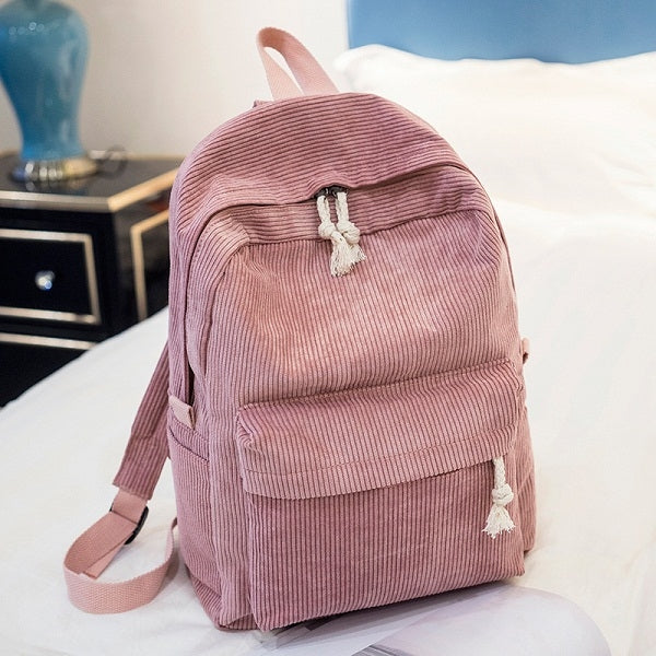 Pink corduroy backpack with front pocket, top flap, tassel drawstring, shoulder straps