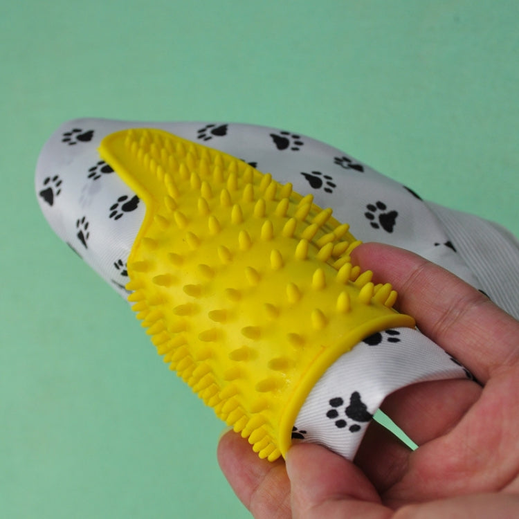 Handheld view of pet grooming glove with yellow silicone nubs and paw-print pattern