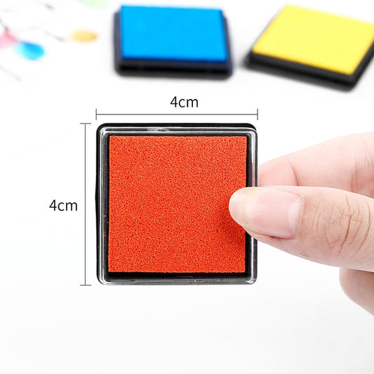 Red 4x4 cm ink pad in black frame, small square sponge held by hand