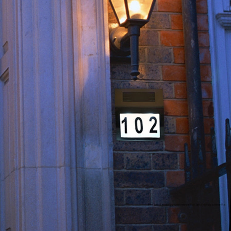 Outdoor solar house number wall light displaying “102” on a brick exterior wall