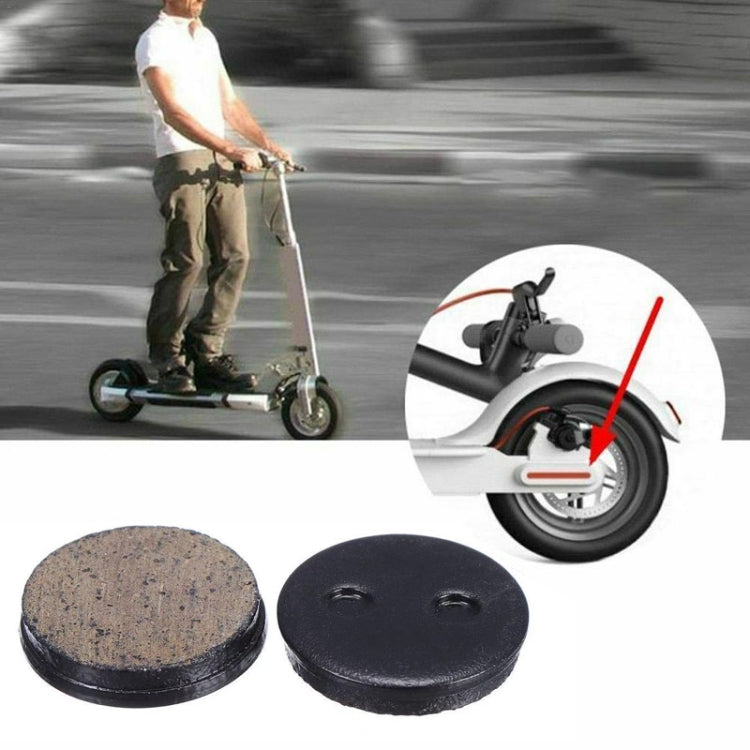 Two round disc brake pads, brown friction face and black backing with bolt slots