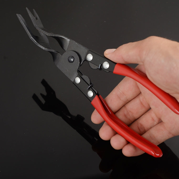 Hand holding red-handled pliers with black jaws and pivot hardware