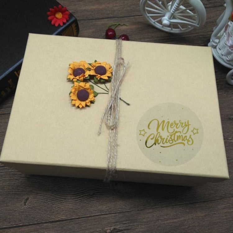 Round “Merry Christmas” gold sticker on gift box wrap, transparent finish