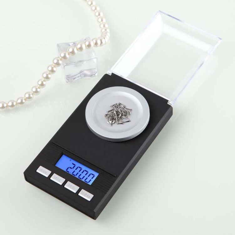 Compact electronic jewelry scale with round pan, clear cover, blue LCD, and metal items