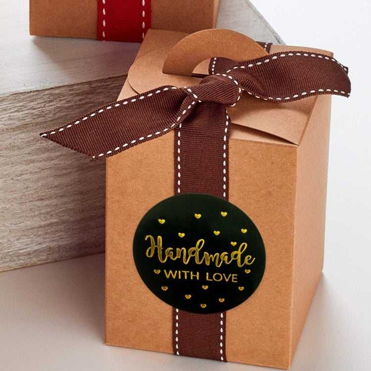 Round black "Handmade with love" sticker on a brown gift bag, gold heart dots