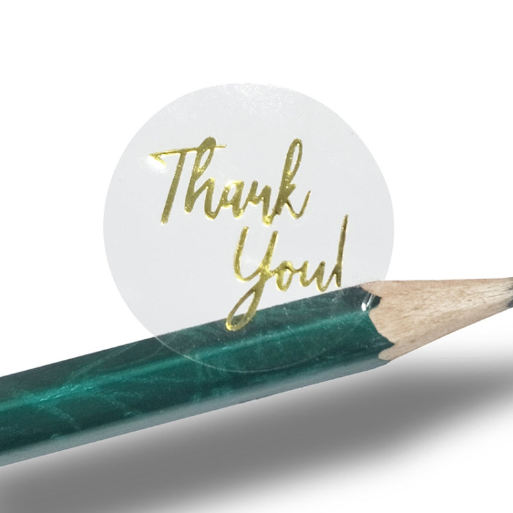 Gold 'Thank You' sticker label being touched by a pencil