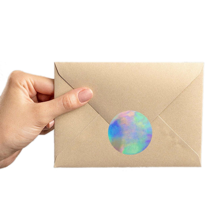 Holographic rainbow heart label sticker being placed on a kraft envelope