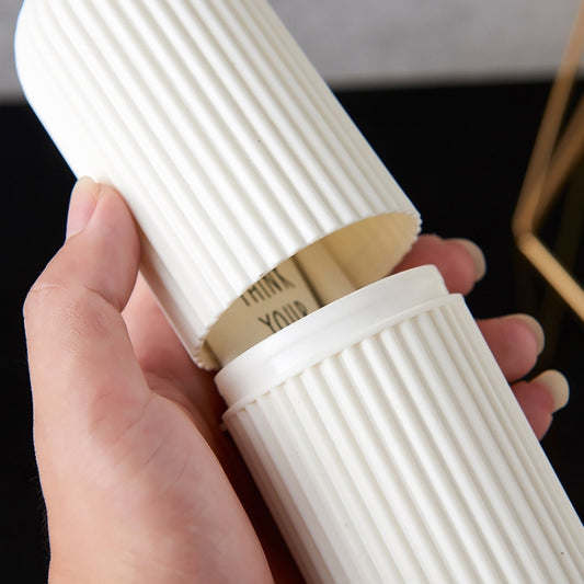 Ribbed white toothbrush storage cup with lid detail, held in hand