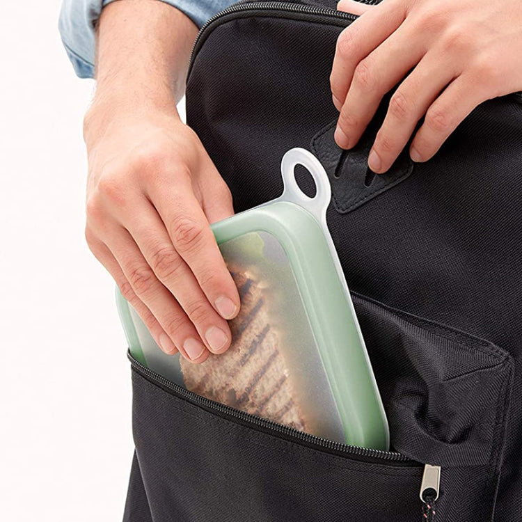 Light green bento lunch box carried in a black office bag pocket