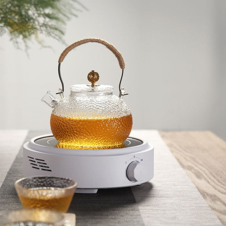 Electric tea cooker stove, white base heating a glass teapot with amber liquid