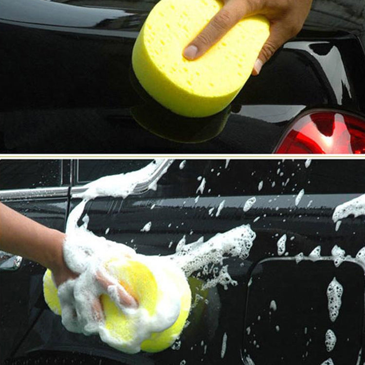 Hand holding a yellow honeycomb car wash sponge with suds for cleaning