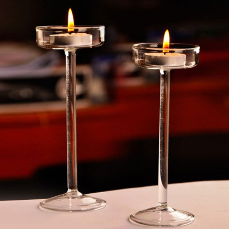 Pair of clear glass candlesticks with lit tea lights, slender stems and flared base