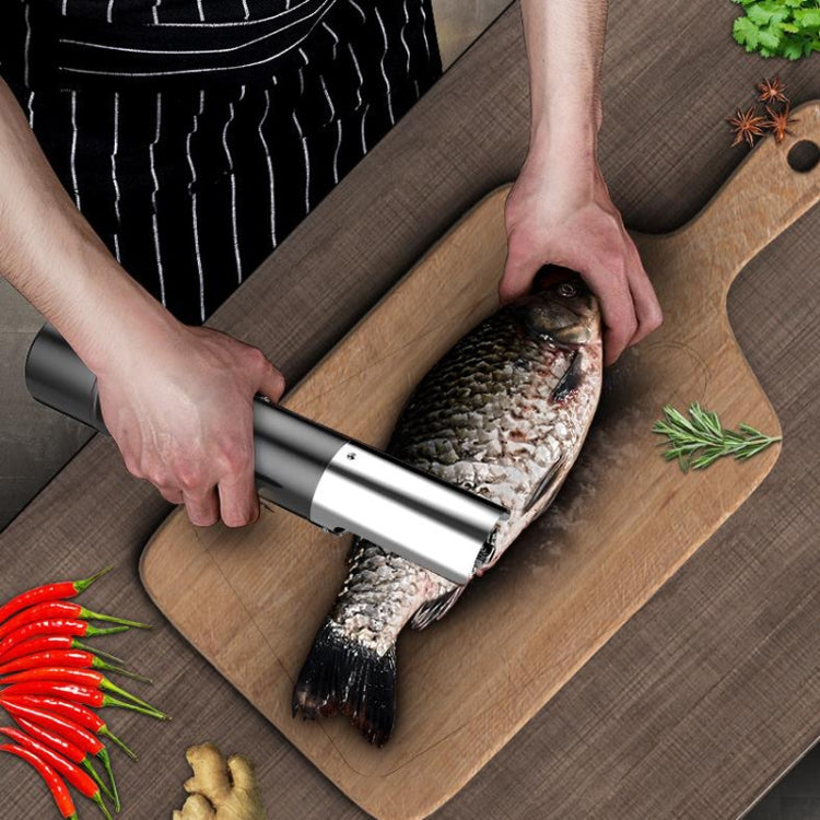 Electric fish scale scraper trimming fish scales on a cutting board with guard